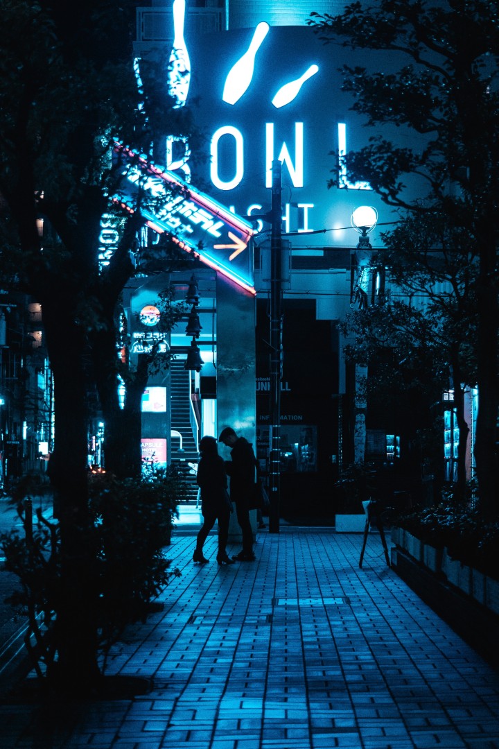Couple silhouettes under blue neon bowling sign at night