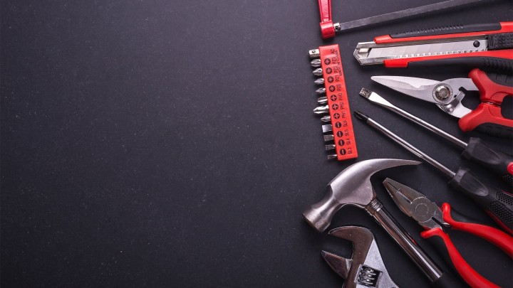 Hand tools and safety gear on wooden background