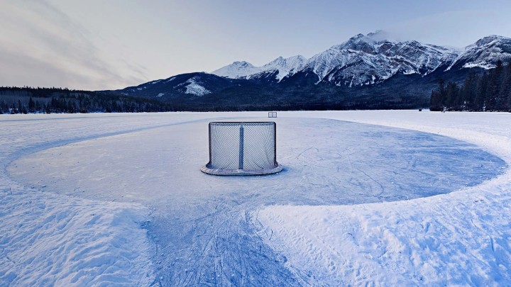 Hockey net on frozen lake mountains background