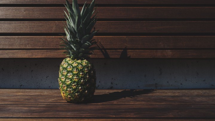 Pineapple on coastal rocks by the sea with cloudy sky