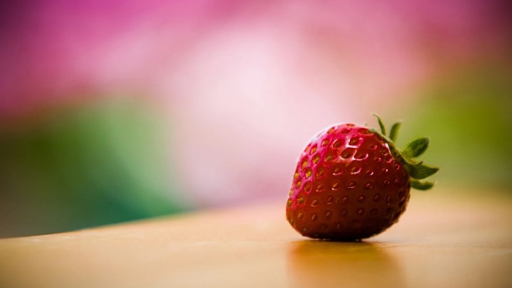 Red strawberry close up on a wooden surface