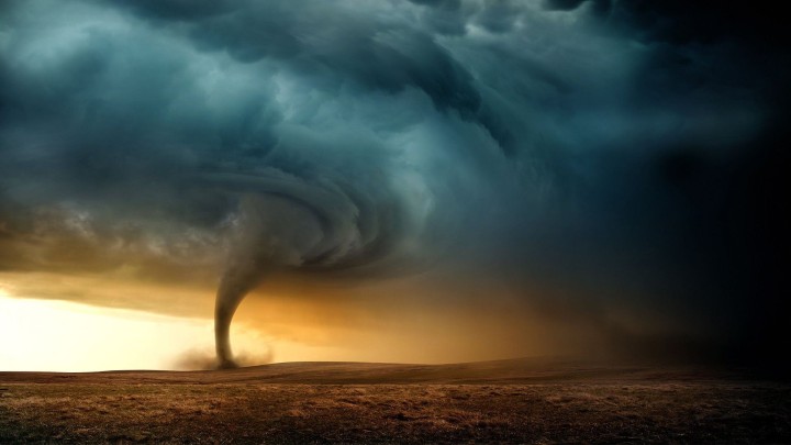 Road leading to a tornado storm cloud over a field