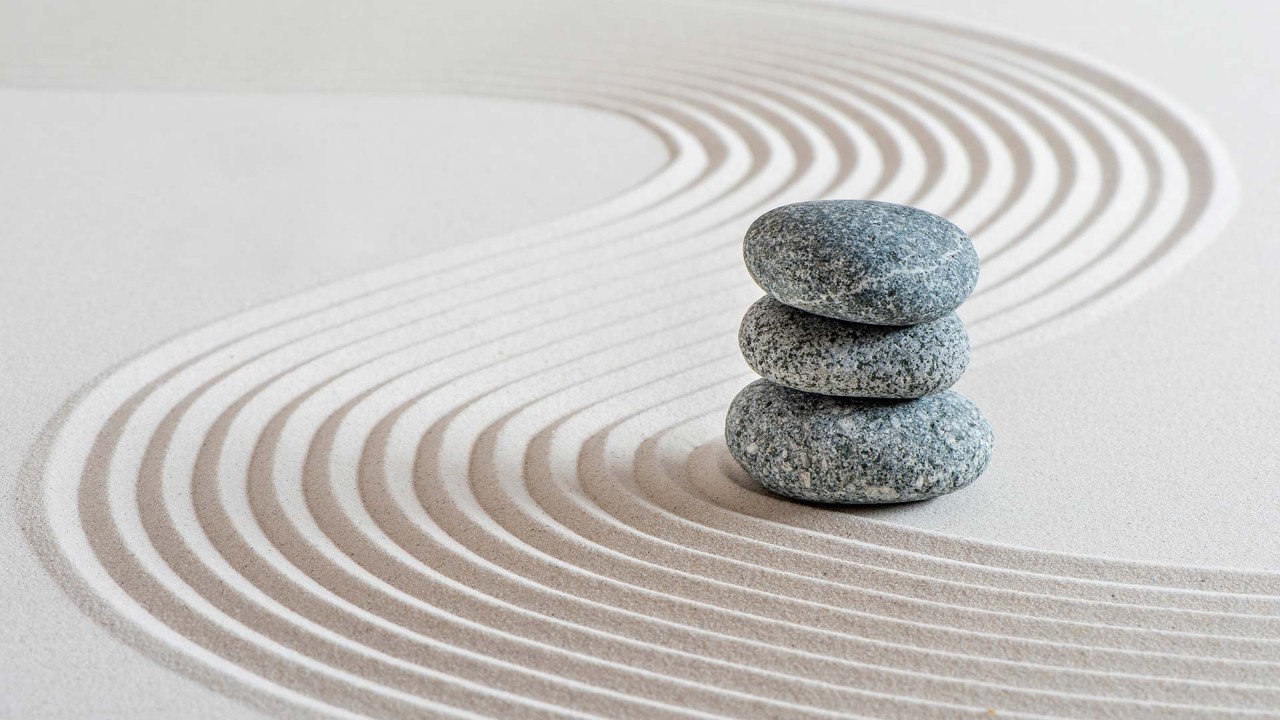 Stacked stones on raked sand in a Zen garden