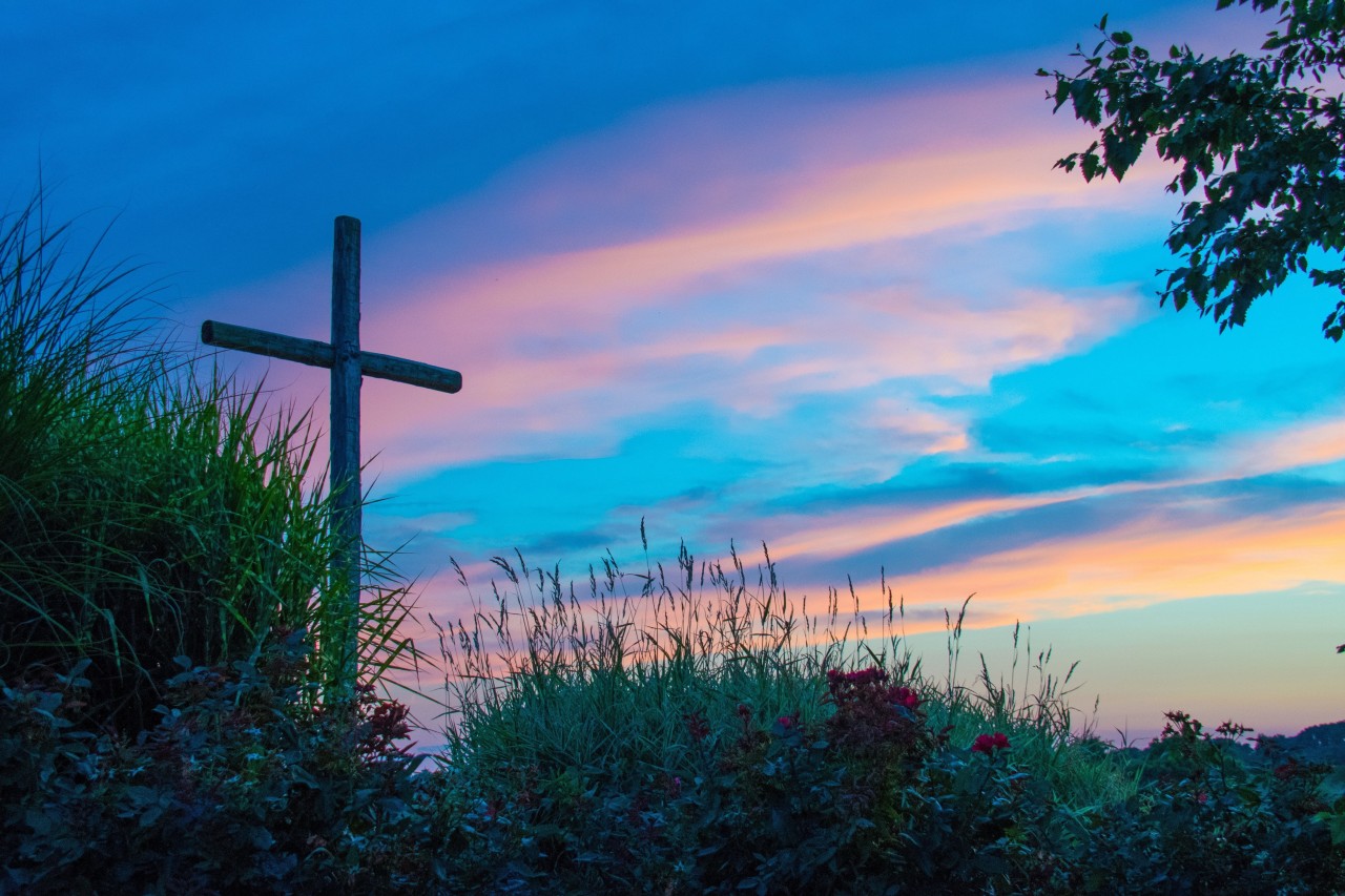 Wooden cross silhouette against sunset sky