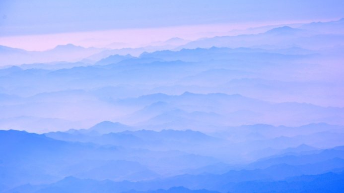 A series of mountains in the distance, with a hazy blue and lavender gradient