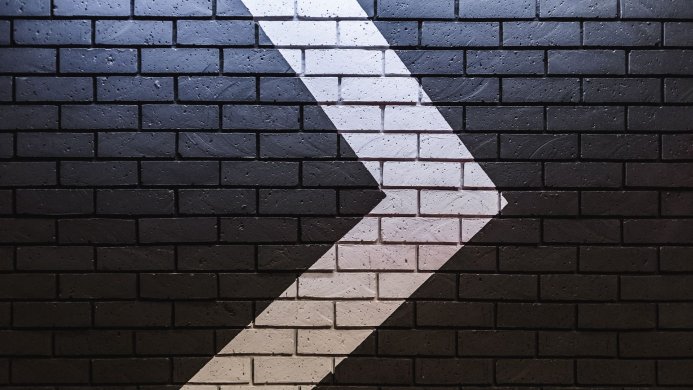 A brick wall with a white arrow pointing to the right
