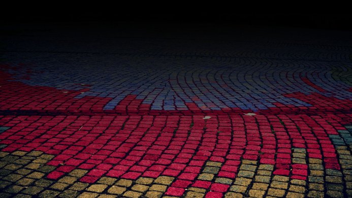 Brick pavement with red, blue, and yellow paint forming a colorful ground texture