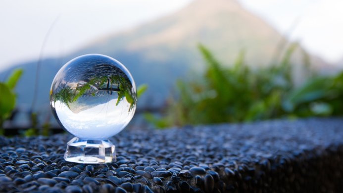 Crystal ball reflecting mountain landscape with ferns on a cobblestone surface