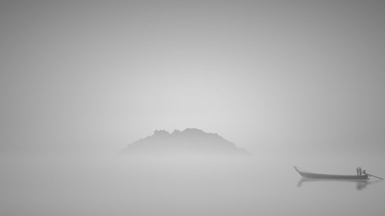 Boat with two people on misty lake near island