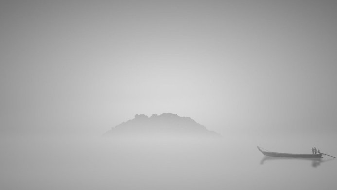 Island and boat with people in a foggy monochrome landscape