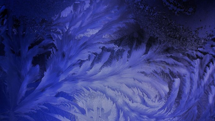 Close up of frost patterns on a window with blue lighting