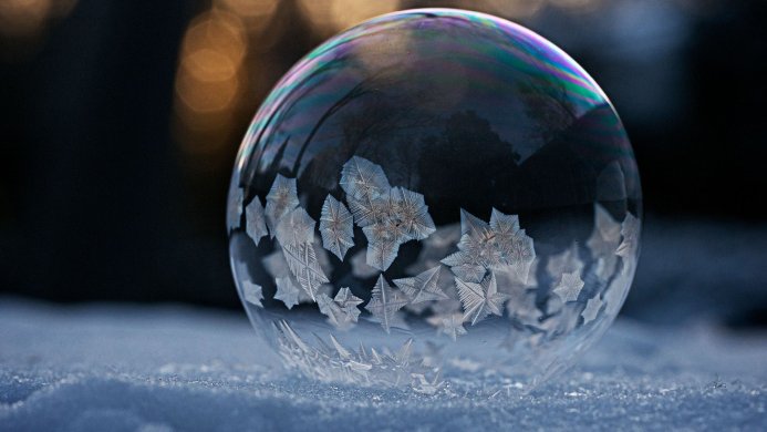 Frozen soap bubble with ice crystals on snow