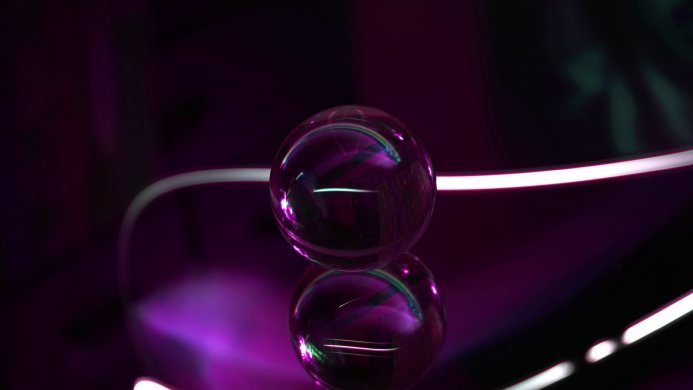 A glass ball reflecting light on a dark purple surface