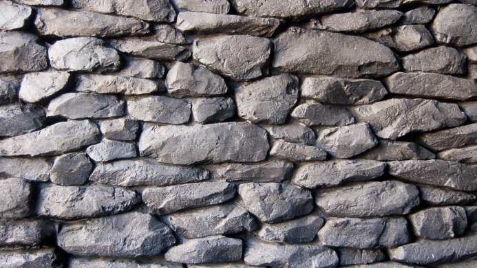 A wall made of gray stones fitted together to form a solid texture
