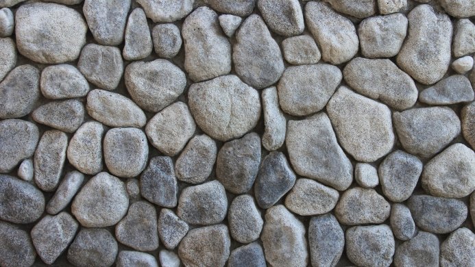 A close-up of a wall made of gray stones of various shapes and sizes
