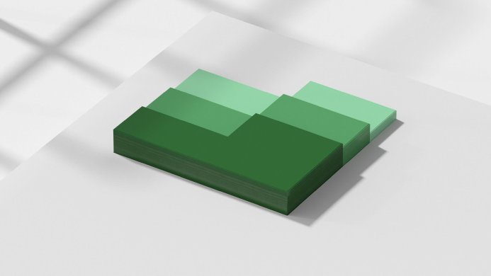 A stack of green paper in various shades on a white surface with shadow