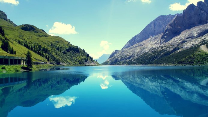 Mountains reflected in a clear, blue lake under a bright sky