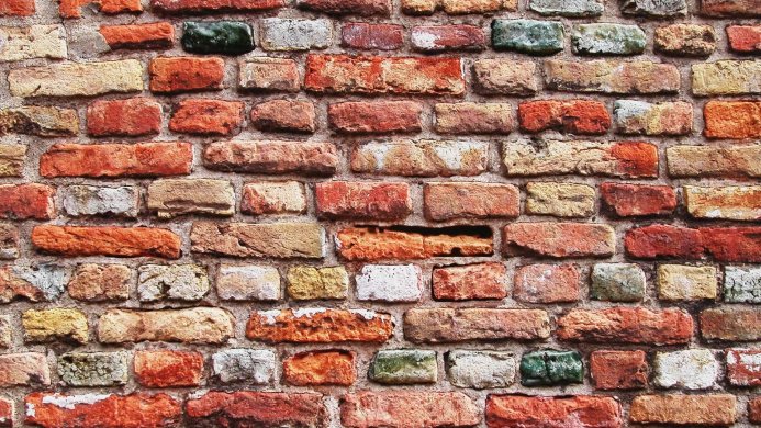 A close-up of an old brick wall with various colored bricks