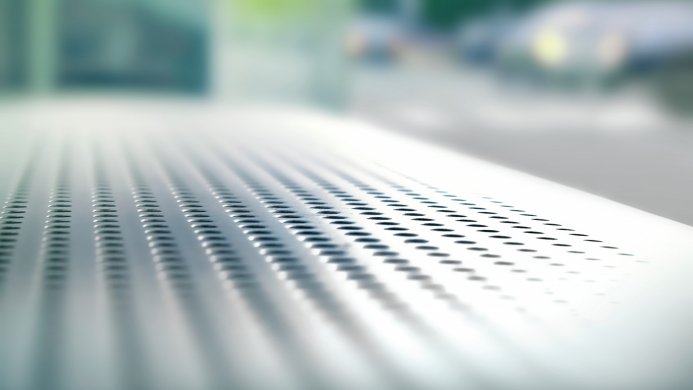 Close-up of a perforated metal surface with blurred background