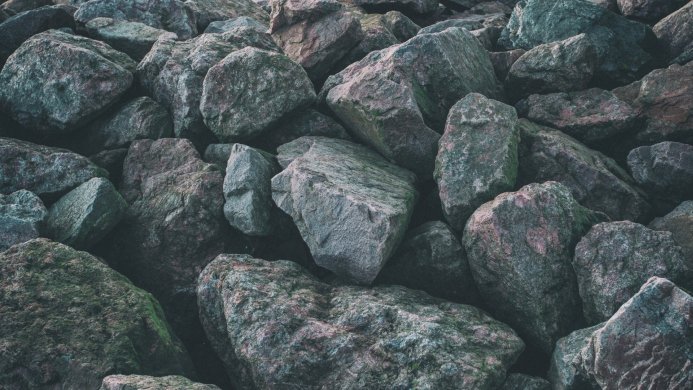 A pile of large rocks and boulders with green moss growing on some of them