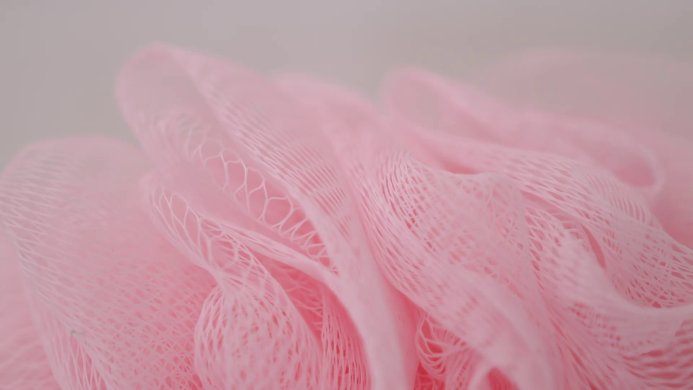 Close up of a pink bath sponge on a blurred background