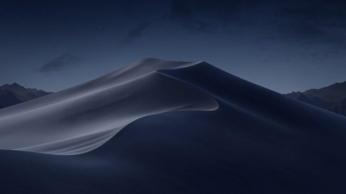 A large sand dune under a night sky with stars, silhouetted mountains in the background