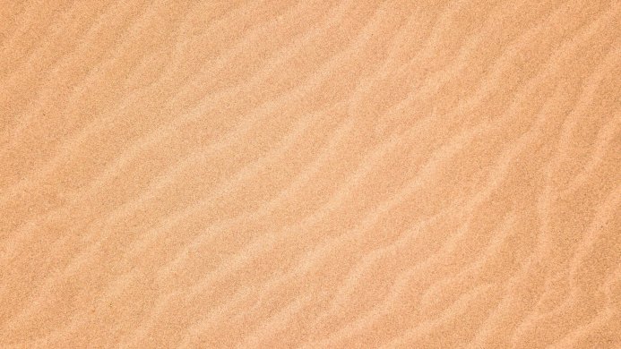 Close-up of rippled sand texture in warm beige tones