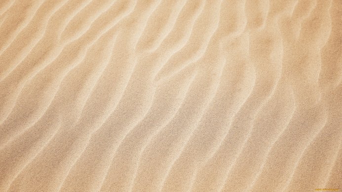 Beige sand with wavy patterns, close-up