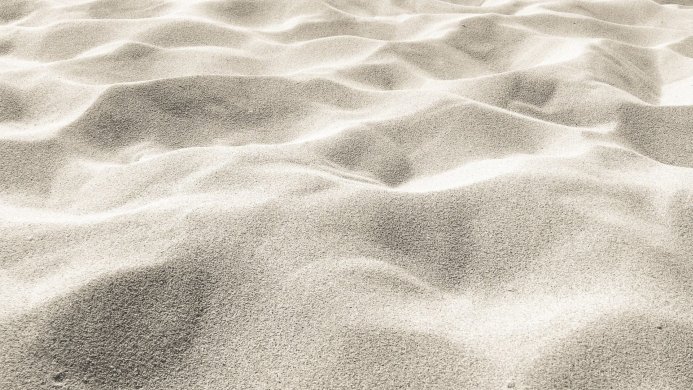 Close-up of textured sand with small dunes and varied shading in a monochrome color palette