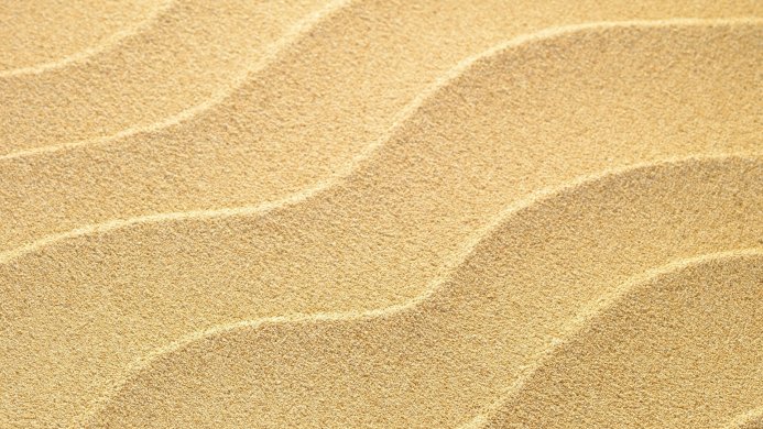 Close-up of sand with wave patterns, beige color