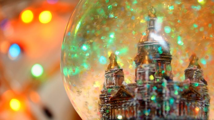 Snow globe with a miniature building inside, surrounded by festive lights