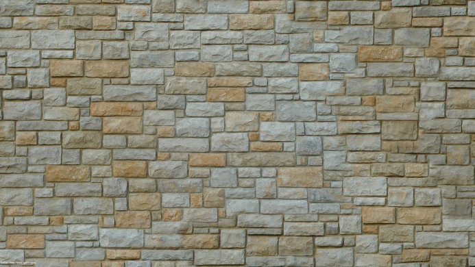 Stone wall with varying sized beige and grey blocks arranged in a random pattern