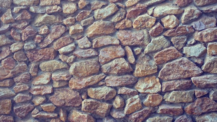 Close-up of a stone wall with various sized rocks and concrete