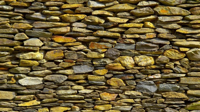 A wall constructed of irregularly shaped stones in shades of yellow, gray, and brown