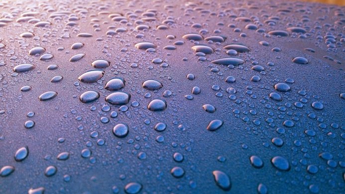 Close up of water droplets on a blue surface, creating a textured pattern