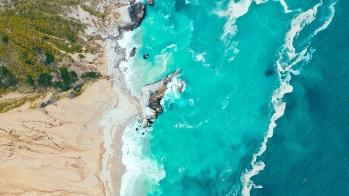 Aerial view of a beach with turquoise water and a sandy shore