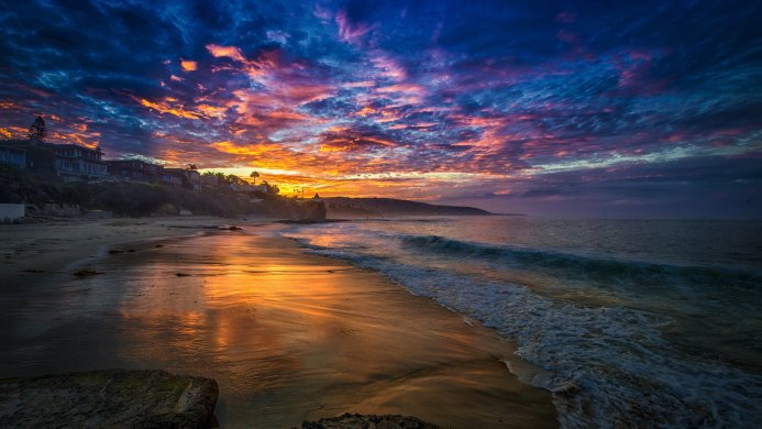 Sunset over the ocean with colorful clouds and a sandy beach