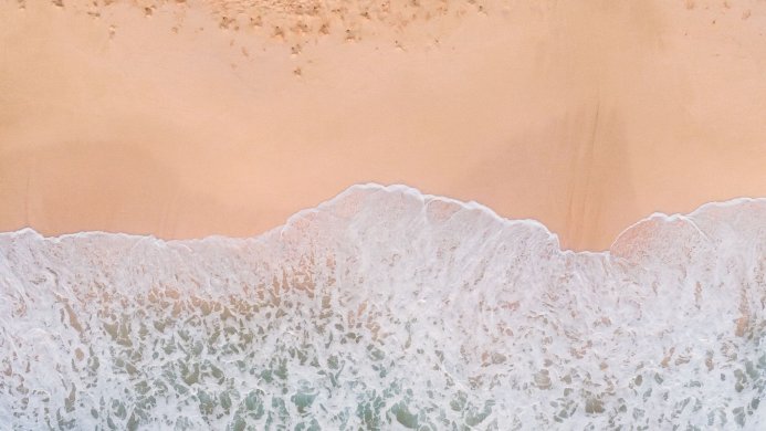 Aerial view of waves washing onto a sandy beach