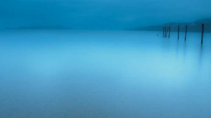 Still blue lake with wooden posts, minimalist landscape