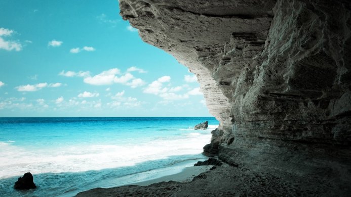 Seascape with a cave, blue sea and cloudy sky