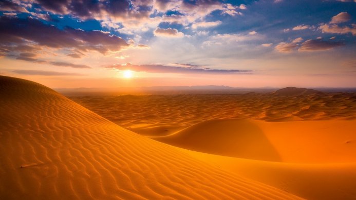 A vast desert landscape with sand dunes at sunset