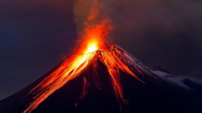 Volcano erupting with lava flowing down its sides against a dark sky