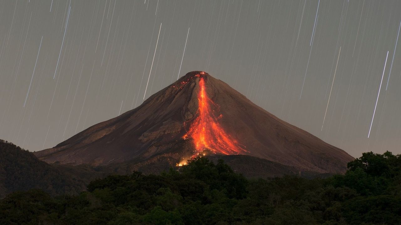 Erupting volcano at night with stars
