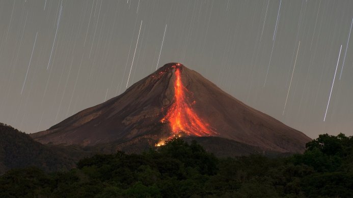 Erupting volcano at night with star trails
