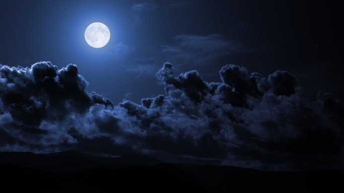 Full moon in a night sky with clouds over the mountains, dark blue background
