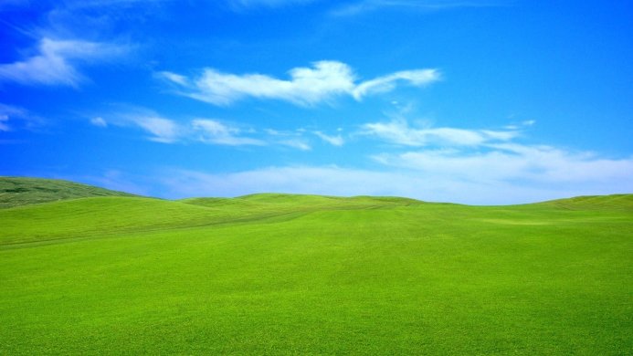 Rolling green hills under a bright blue sky with scattered white clouds