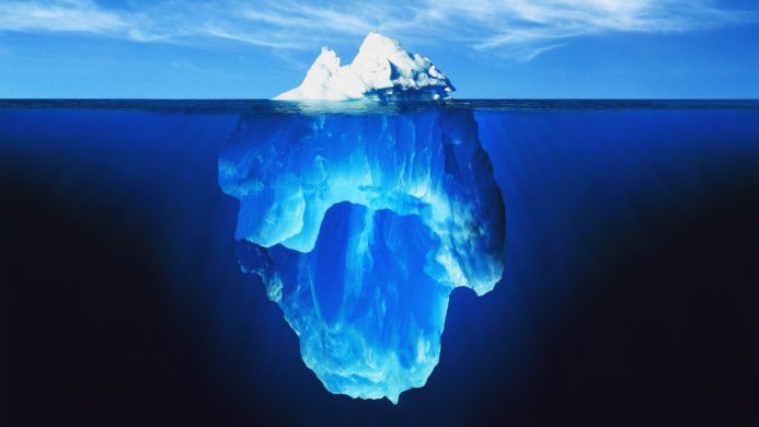 An iceberg with most of its mass underwater, illuminated by sunlight filtering through the deep blue ocean