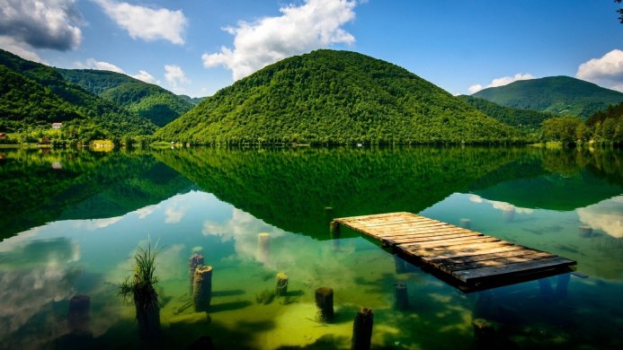 Lake with mountains reflected in the water and a wooden dock in the foreground