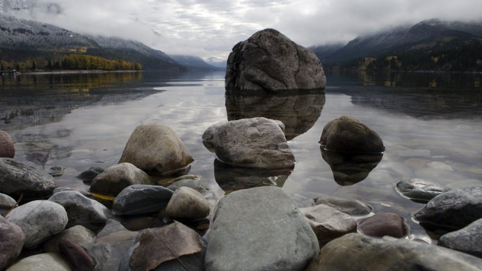 Rocks in lake with mountain backdrop on cloudy day