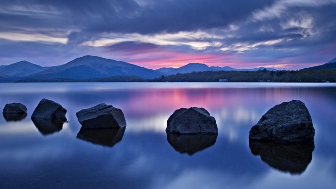 Rocks in a lake reflecting the sky at sunset